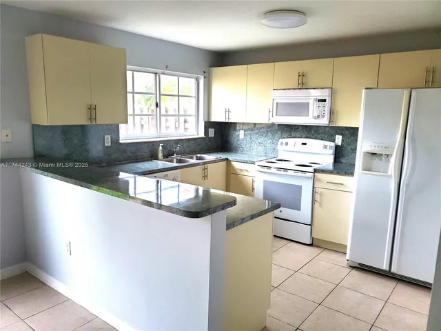 a kitchen with white cabinets and white appliances
