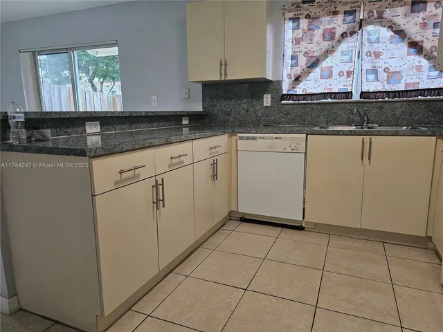 a kitchen with granite countertop white cabinets and window