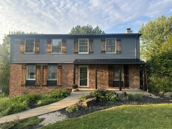a view of a brick house with a yard and plants