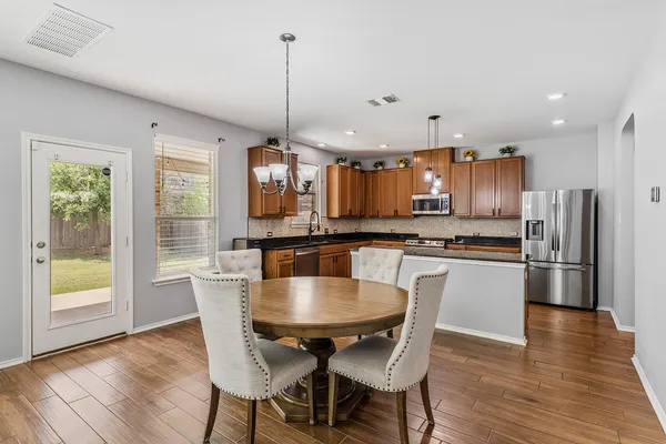 a kitchen with stainless steel appliances granite countertop a stove a refrigerator a kitchen island a dining table and chairs