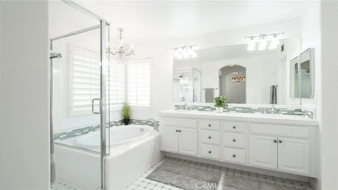 a spacious bathroom with double vanity a window a large mirror and a bathtub