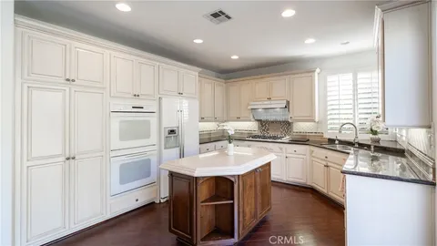 a kitchen with granite countertop white cabinets and white appliances