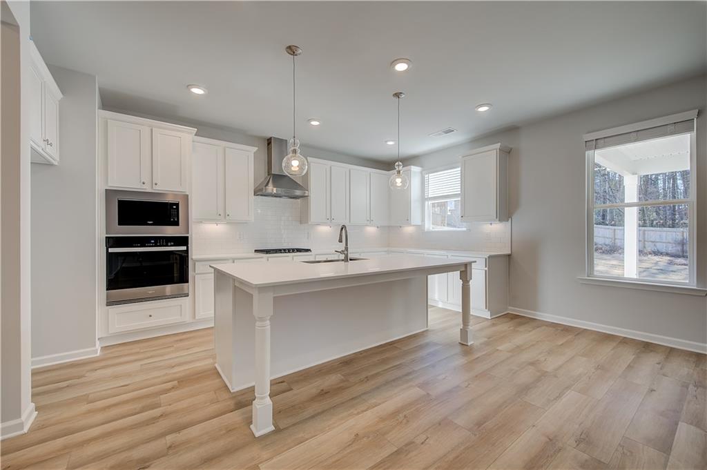 309 Exeter Court Stockbridge, GA 30281 - Photo 11 of 34 a kitchen with stainless steel appliances kitchen island granite countertop a stove a sink and white cabinets with wooden floor