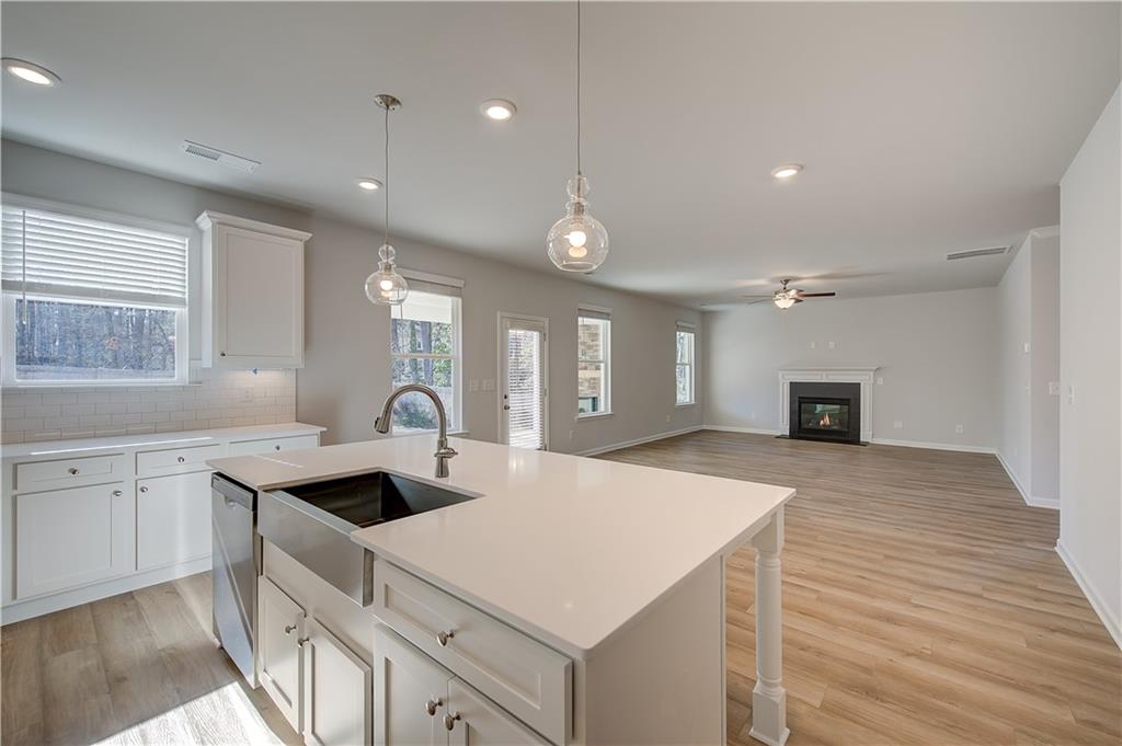 309 Exeter Court Stockbridge, GA 30281 - Photo 12 of 34 a kitchen with a sink dishwasher a stove and white cabinets with wooden floor