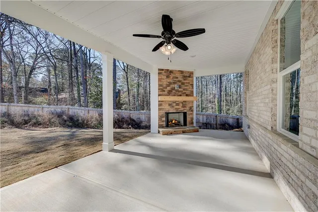 a view of a livingroom with a fireplace a ceiling fan and windows