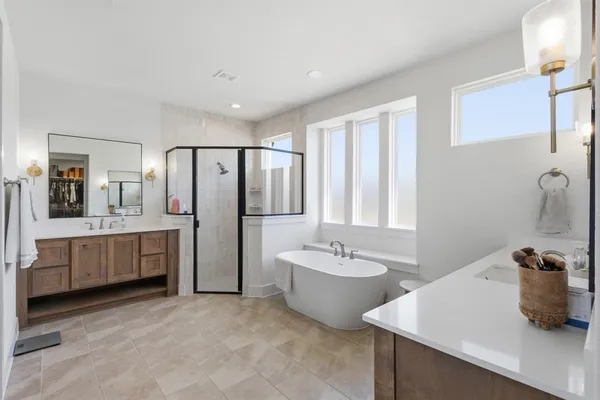 a bathroom with a tub sink double vanity and mirror