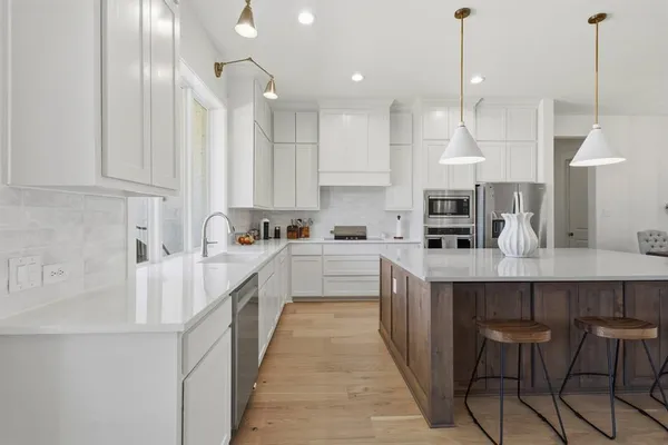 a large kitchen with kitchen island white cabinets and stainless steel appliances