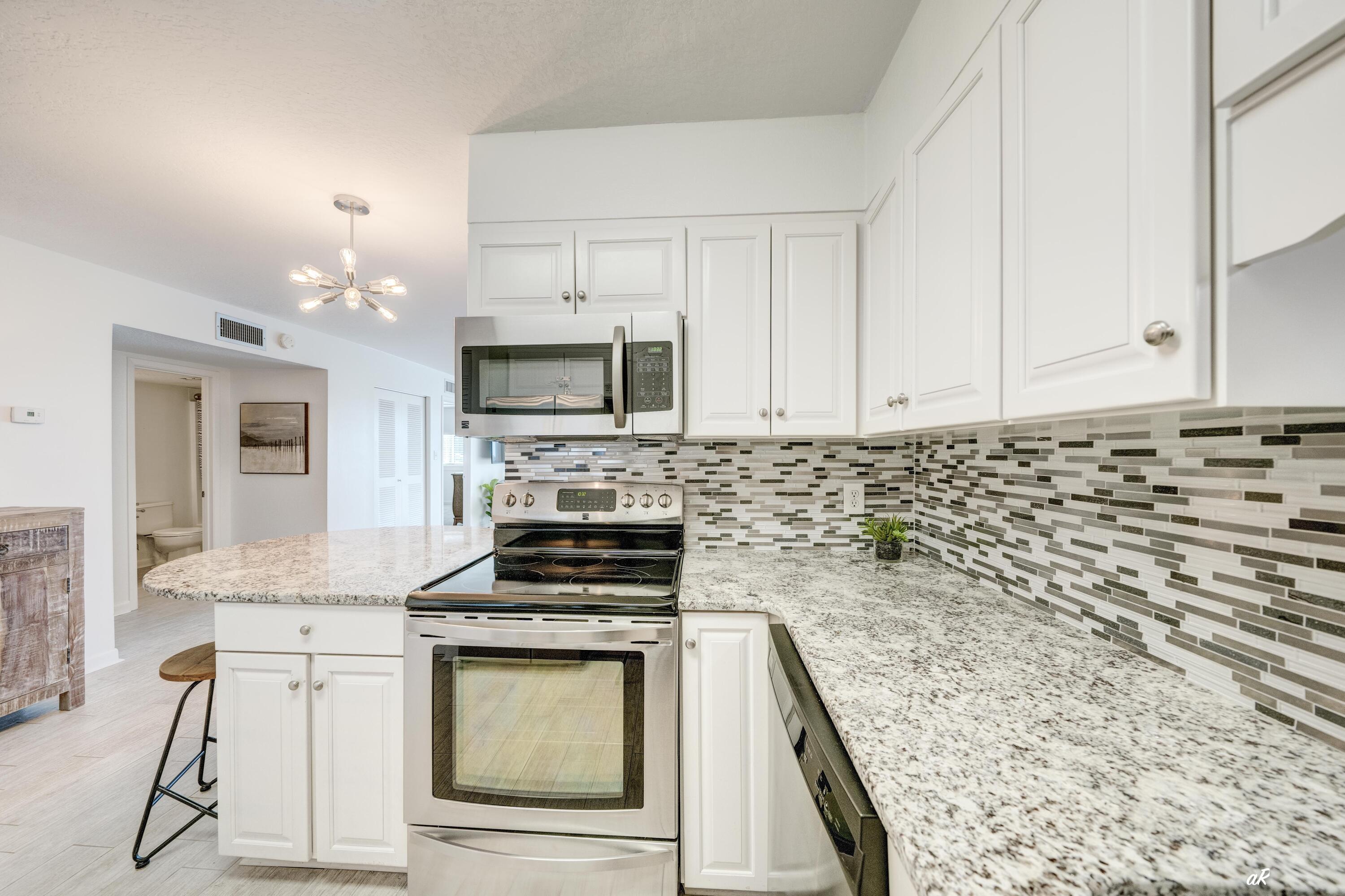30 Moreno Point Road, Unit 404A Destin, FL 32541 - Photo 7 of 52 a kitchen with granite countertop a stove sink and cabinets