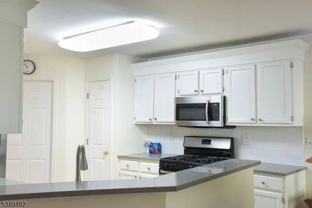 a kitchen with granite countertop white cabinets and stainless steel appliances