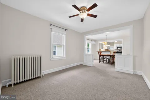 an empty room with chandelier fan and windows