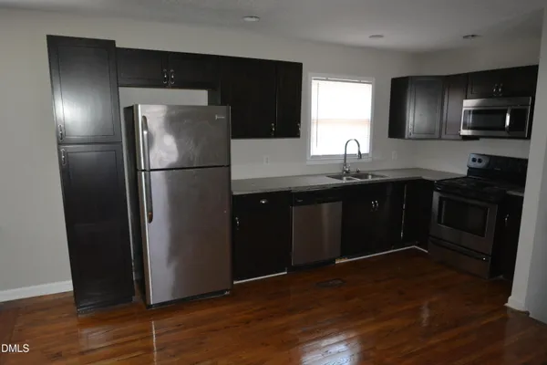 a kitchen with a sink a refrigerator freezer a stove and a wooden floor