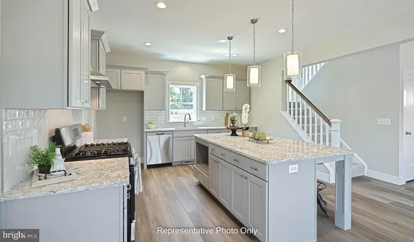 a kitchen with a stove a sink a refrigerator and a wooden floor