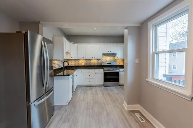 a kitchen with granite countertop stainless steel appliances a refrigerator cabinets and wooden floor