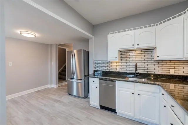 a kitchen with stainless steel appliances granite countertop a sink and a refrigerator