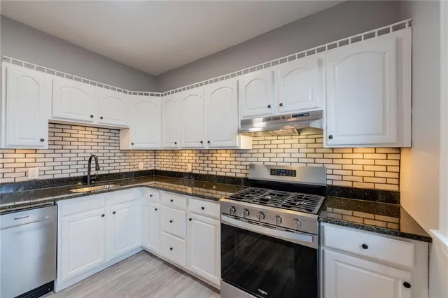 a kitchen with granite countertop a stove sink and cabinets