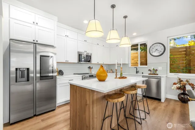 a kitchen with a refrigerator a stove a sink and dishwasher with wooden floor