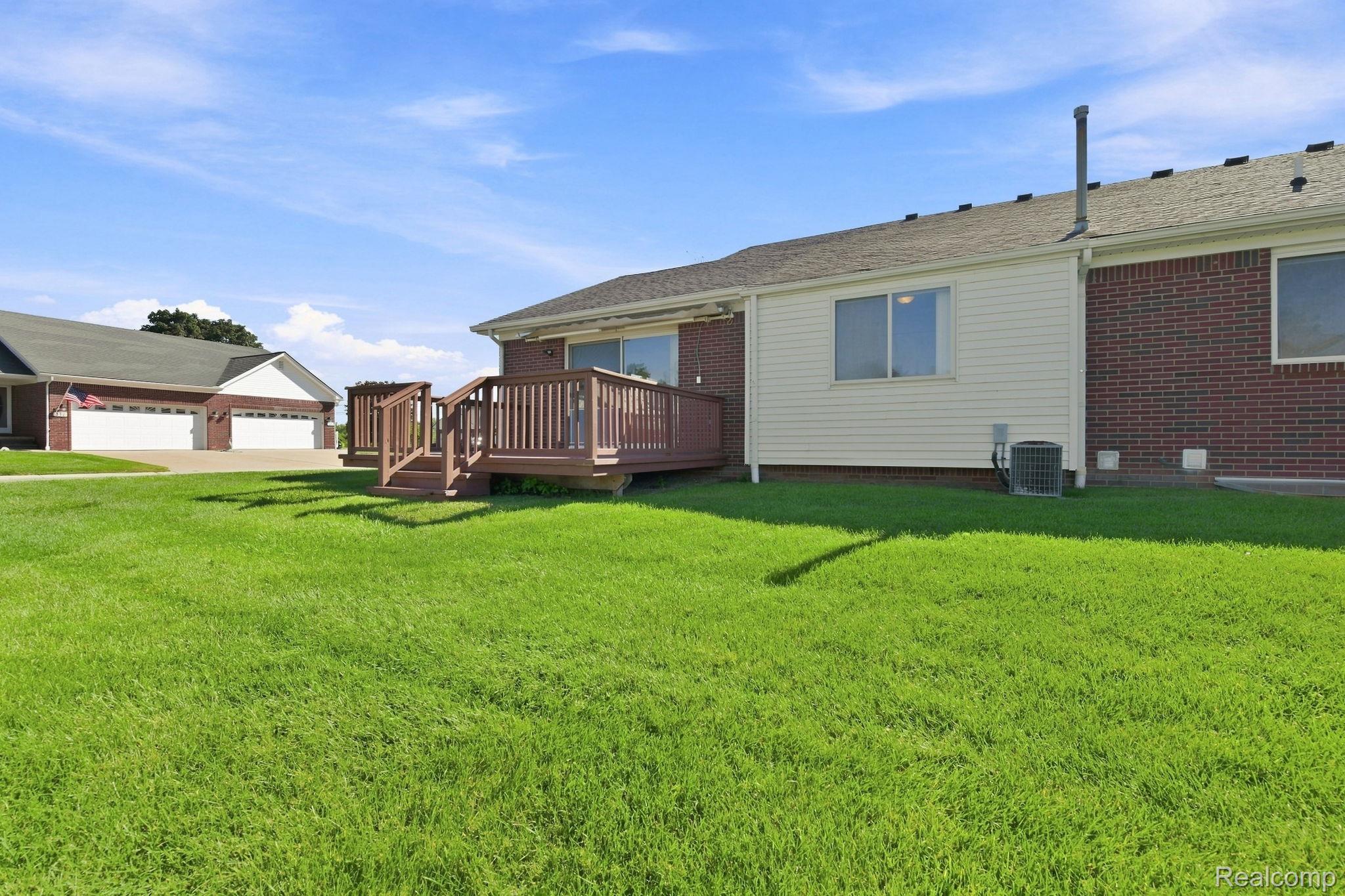 493 Harvard Drive Romeo, MI 48065 - Photo 32 of 36 Expansive green lawn with a wooden deck featuring railings and steps