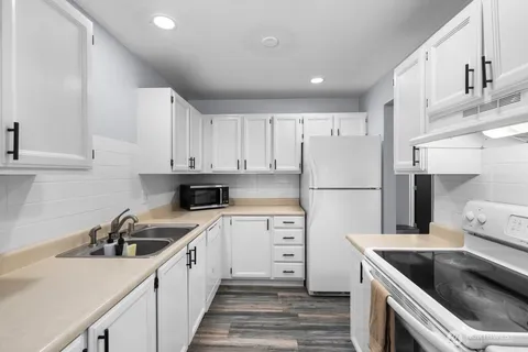 a kitchen with white cabinets sink and white appliances