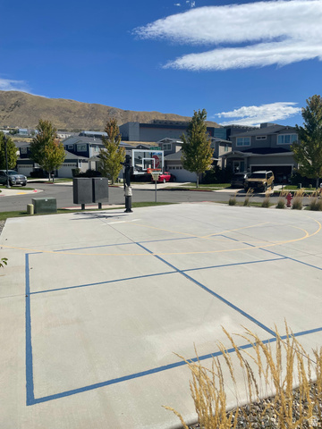 14760 Rising Star Way, Unit 71 Bluffdale, UT 84065 - Photo 7 of 41 Paved recreational court with basketball hoop, surrounded by residential street, landscaping, and distant mountains