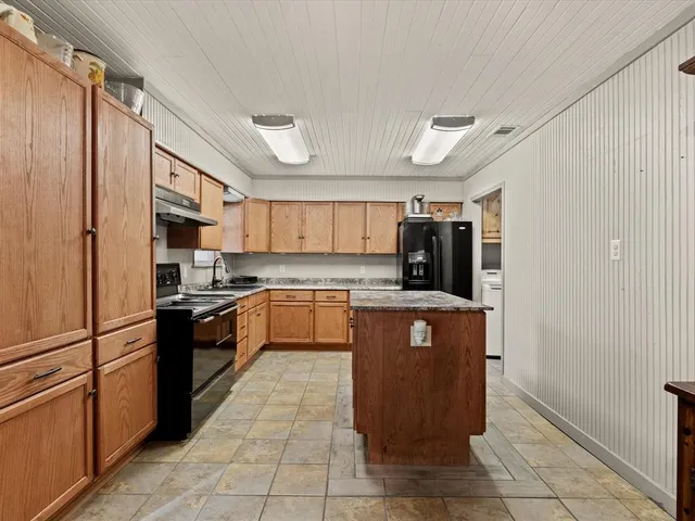a large kitchen with stainless steel appliances granite countertop a refrigerator and a sink