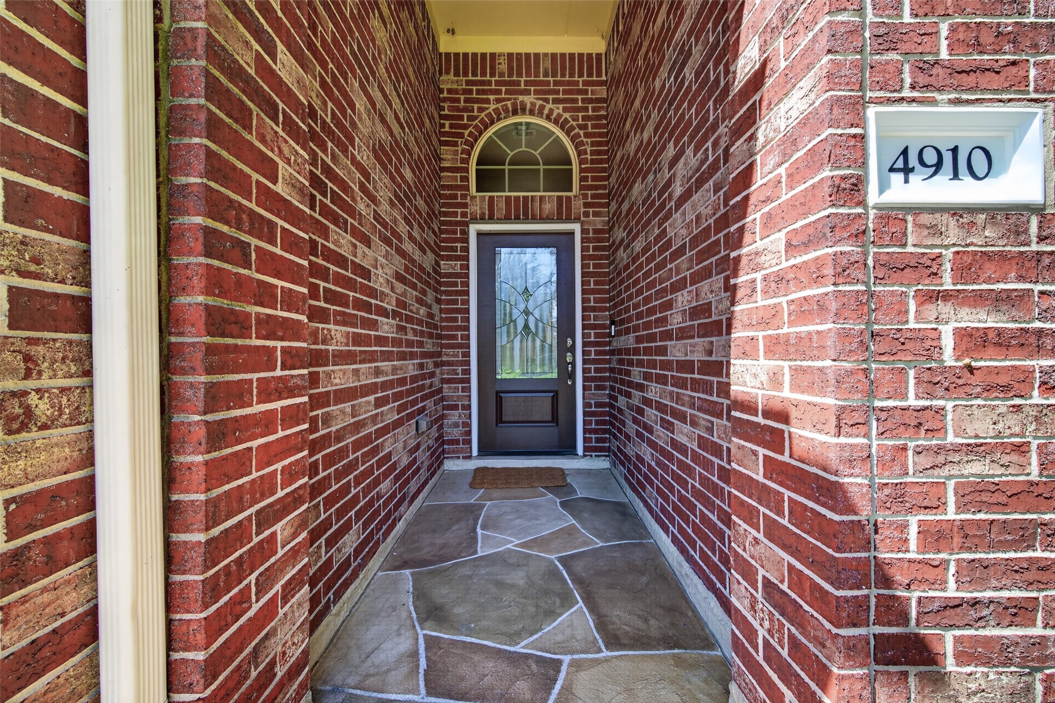 4910 Culver Lane Rosenberg, TX 77471 - Photo 6 of 50 Your welcoming brick entrance with a decorative, CARVED STONE WALKWAY leading to a CUSTOM SOLID WOOD DOOR with LEADED GLASS, installed 2025. With the house number clearly displayed at front door entrance, family and friends will find you more quickly!