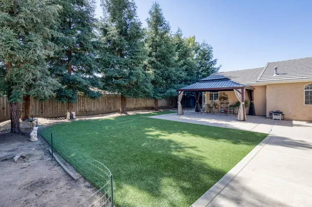 a view of a patio with a table and chairs under an umbrella with a small yard