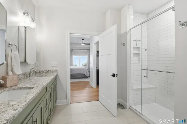 a bathroom with a granite countertop sink a mirror and shower