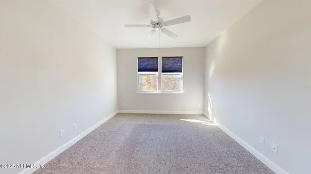 an empty room with windows and chandelier fan