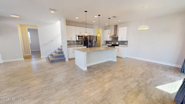 a view of kitchen with kitchen island a sink a stove a refrigerator cabinets and a living room view