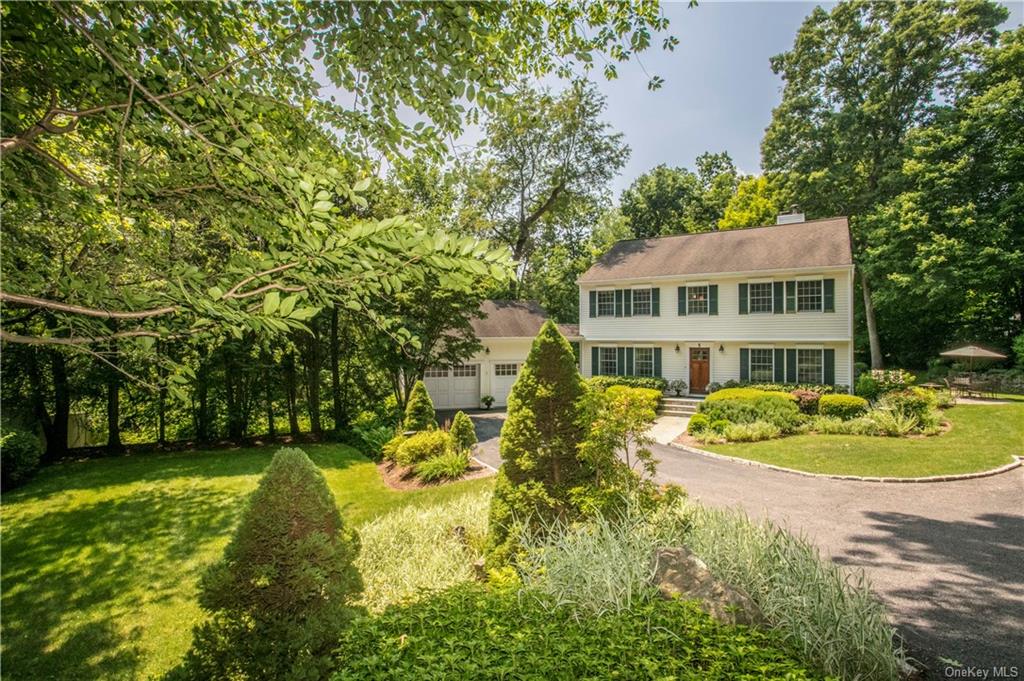 a front view of a house with a garden and lake view