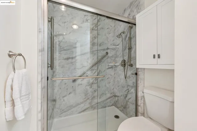 a bathroom with a granite countertop sink a toilet a mirror a vanity a bathtub and shower