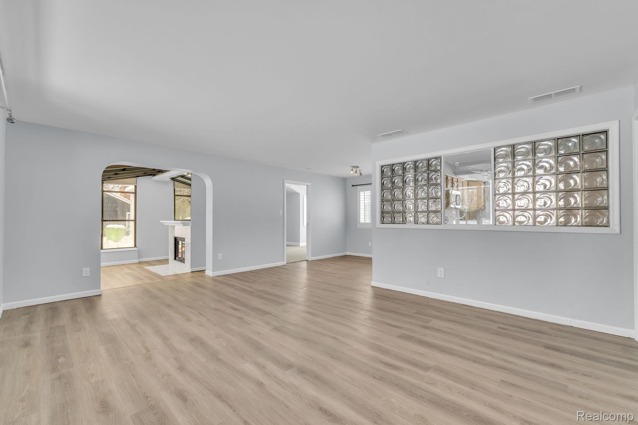 6576 Inkster Road West Bloomfield, MI 48322 - Photo 12 of 62 Unfurnished living room featuring a fireplace, plenty of natural light, arched walkways, and light wood-style flooring