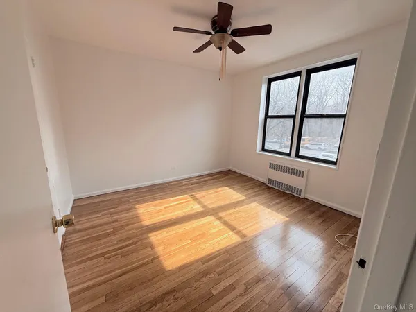 a view of empty room with wooden floor and fan