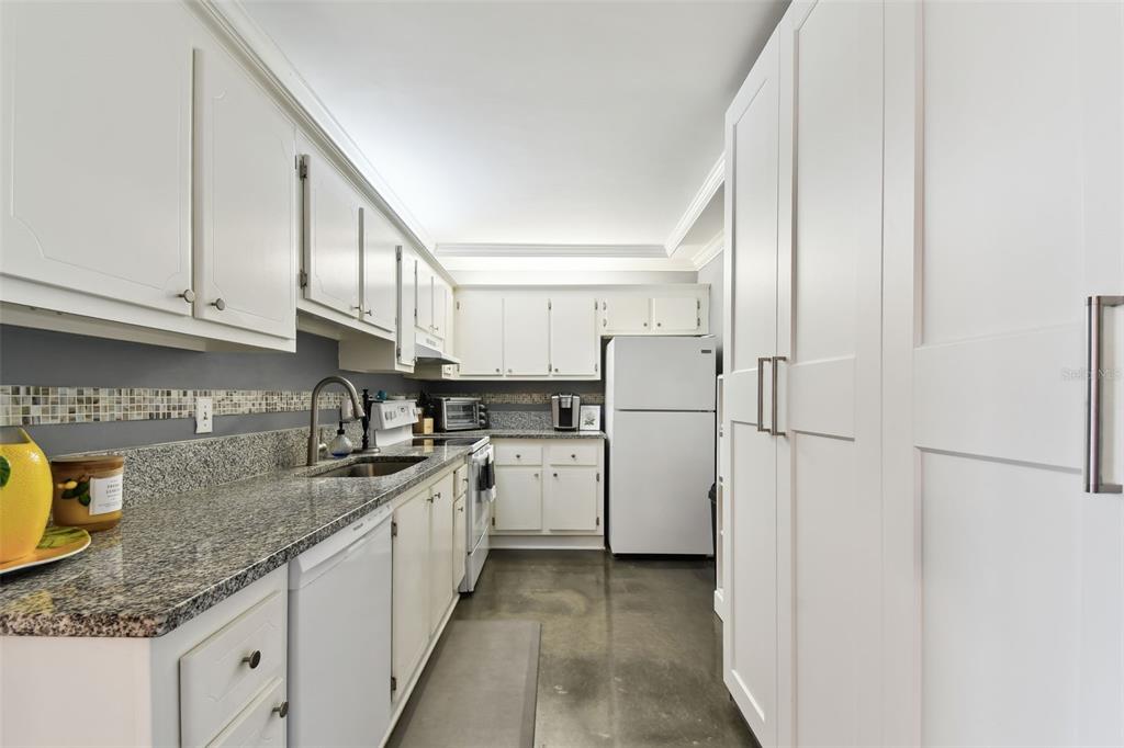 255 Dolphin Point, Unit 207 Clearwater Beach, FL 33767 - Photo 11 of 69 a kitchen with stainless steel appliances granite countertop a refrigerator a stove and a sink