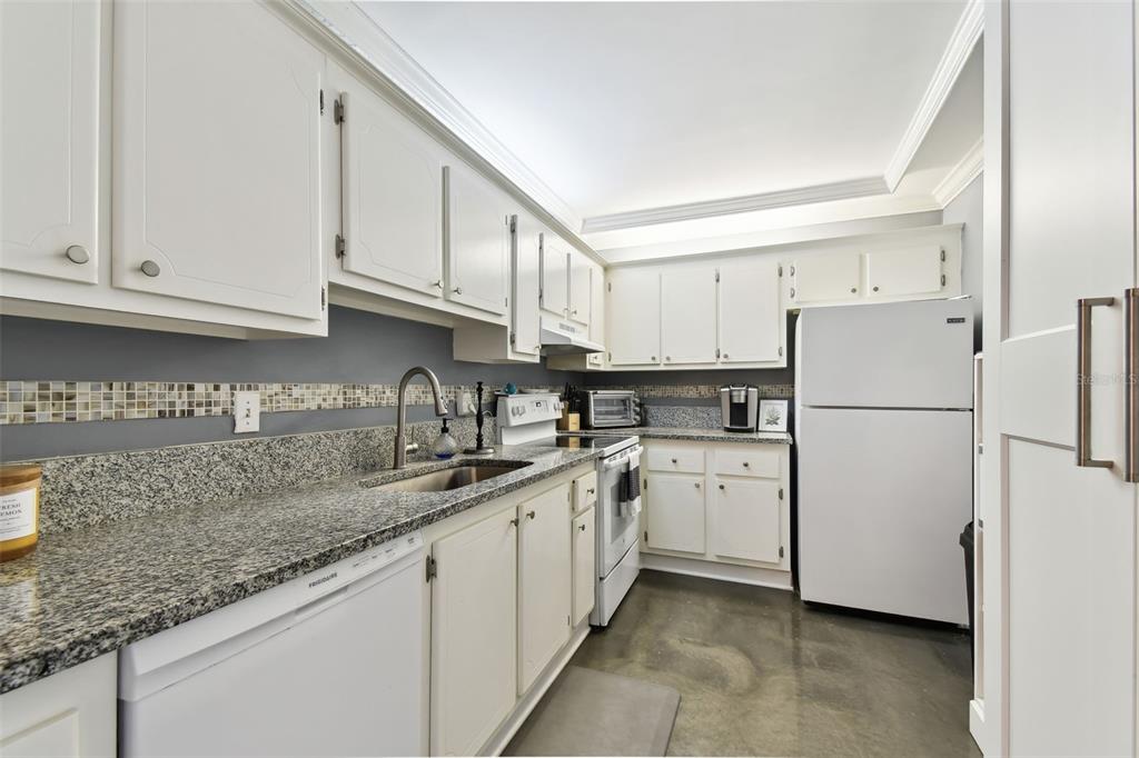 255 Dolphin Point, Unit 207 Clearwater Beach, FL 33767 - Photo 12 of 69 a kitchen with white cabinets sink and white appliances