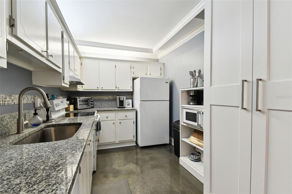 255 Dolphin Point, Unit 207 Clearwater Beach, FL 33767 - Photo 13 of 69 a kitchen with a refrigerator sink and white cabinets