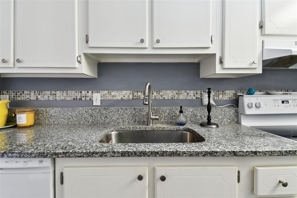 255 Dolphin Point, Unit 207 Clearwater Beach, FL 33767 - Photo 16 of 69 a kitchen with granite countertop white cabinets and a sink