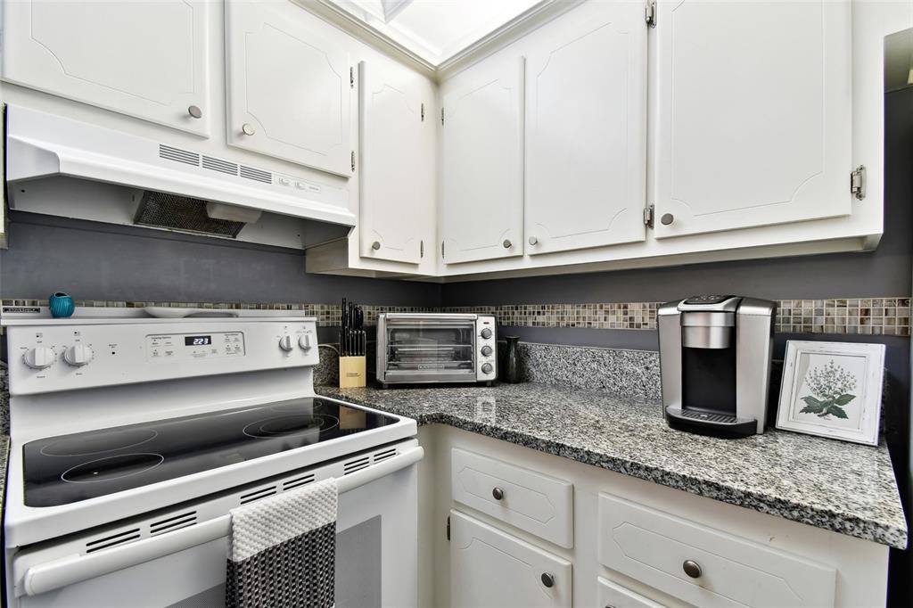 255 Dolphin Point, Unit 207 Clearwater Beach, FL 33767 - Photo 17 of 69 a kitchen with granite countertop a sink and white cabinets