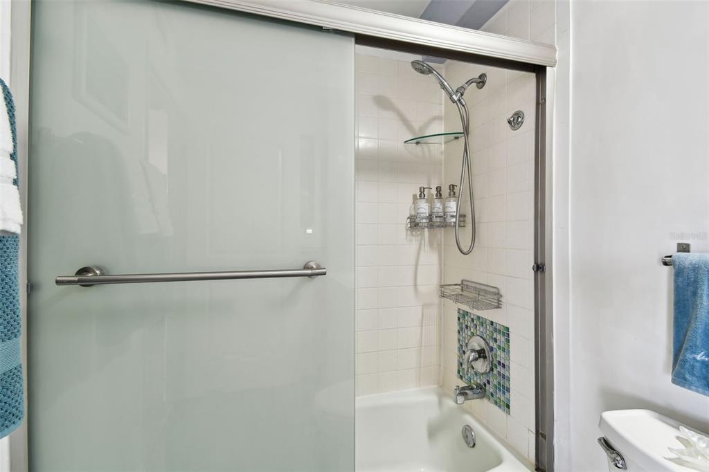 255 Dolphin Point, Unit 207 Clearwater Beach, FL 33767 - Photo 28 of 69 a bathroom with a glass shower door