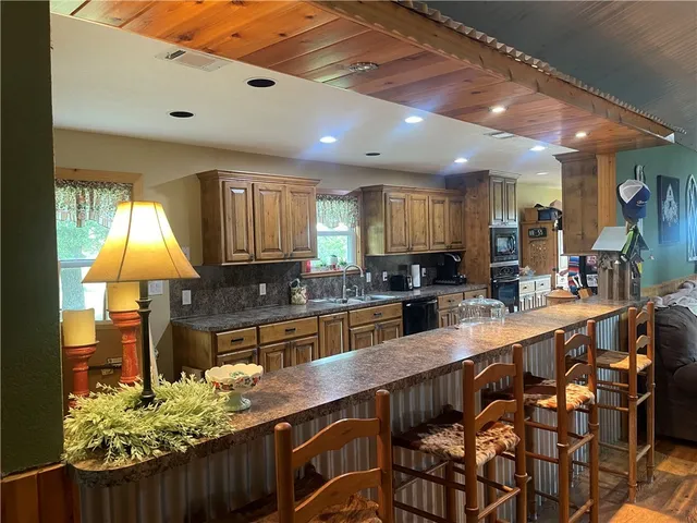 a kitchen with stainless steel appliances granite countertop a sink a stove and a wooden cabinets