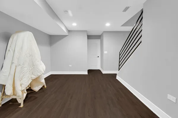 a view of an empty room with wooden floor and stairs