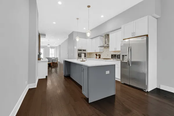 a kitchen with stainless steel appliances granite countertop a refrigerator a sink dishwasher a stove and a refrigerator with wooden floor