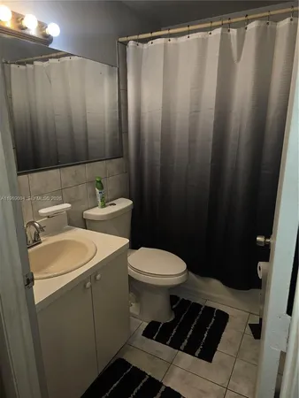 a bathroom with a sink a toilet a mirror and shower curtain