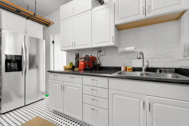 a kitchen with stainless steel appliances granite countertop a sink a refrigerator and white cabinets