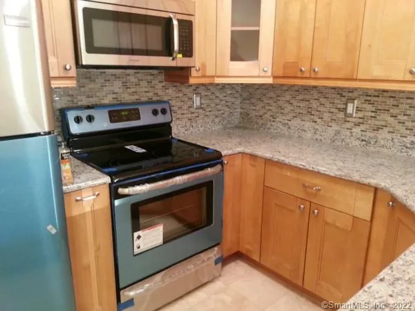a kitchen with granite countertop white cabinets appliances and a window