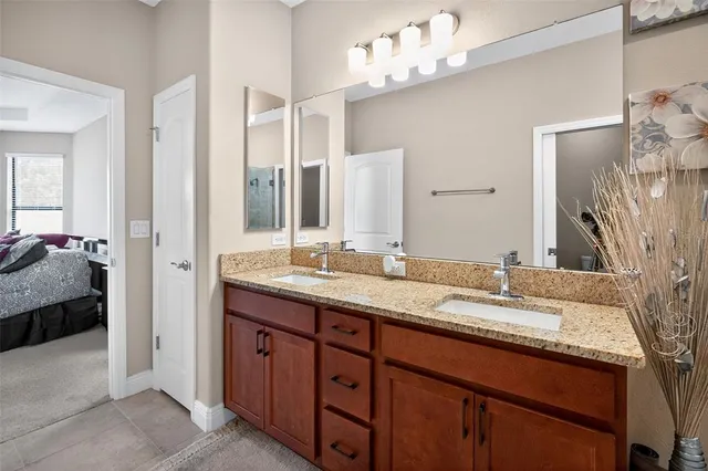 a en suite bathroom with a granite countertop double vanity sink and a mirror