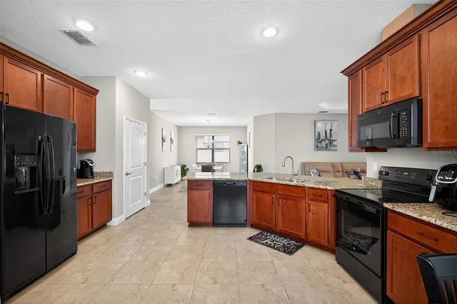 a large kitchen with stainless steel appliances granite countertop a stove sink refrigerator and cabinets