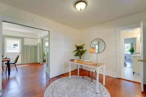 a living room with furniture a rug and a large mirror next to a window