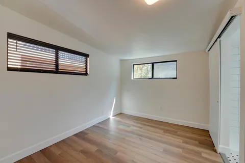 a view of empty room with wooden floor and window