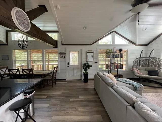 a living room with furniture a large window and wooden floor